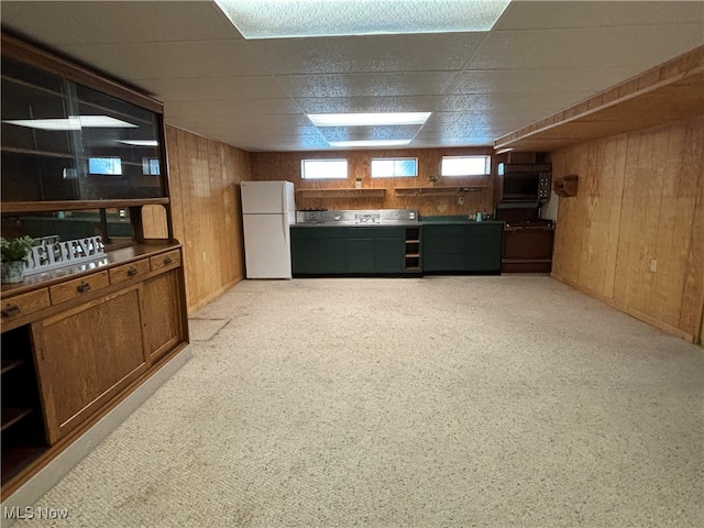 interior space featuring wood walls, a paneled ceiling, white refrigerator, and light colored carpet