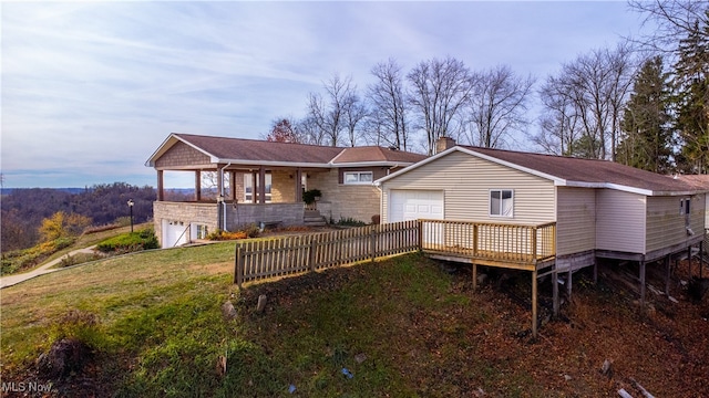 back house at dusk with a lawn, a garage, and a deck