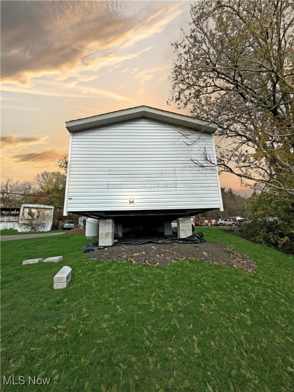 property exterior at dusk with a lawn