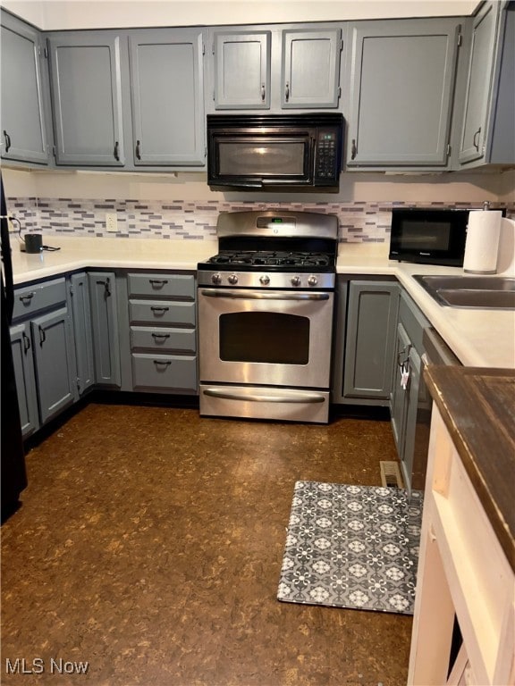 kitchen with gray cabinets, stainless steel gas stove, and tasteful backsplash