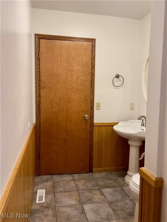 bathroom featuring wood walls, tile patterned floors, and toilet