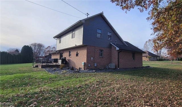 view of side of home with a yard, a deck, and central air condition unit