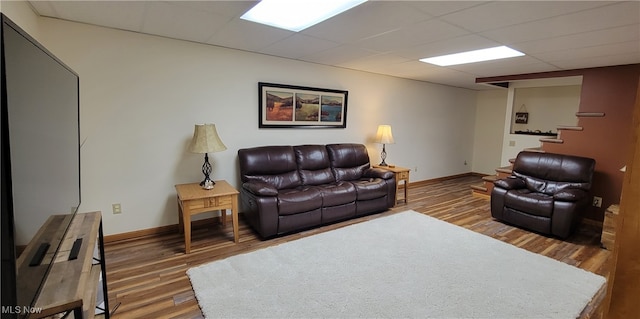 living room featuring wood-type flooring and a drop ceiling