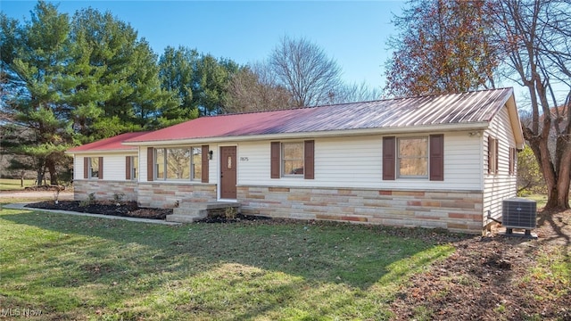 ranch-style home with central air condition unit and a front lawn