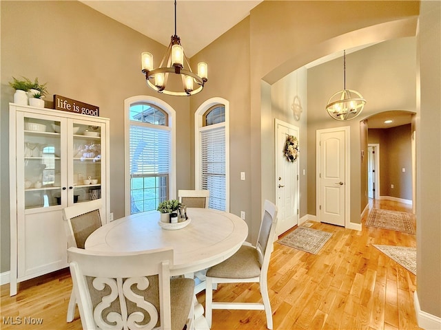 dining room featuring light hardwood / wood-style floors, high vaulted ceiling, and a chandelier