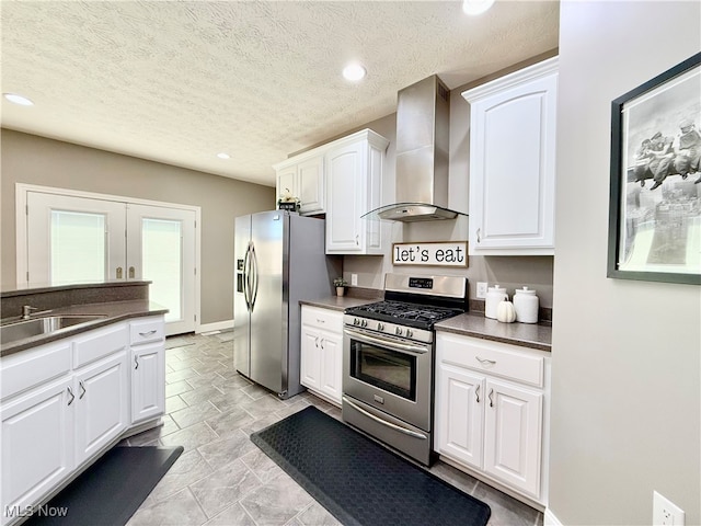 kitchen with sink, wall chimney exhaust hood, a textured ceiling, white cabinets, and appliances with stainless steel finishes