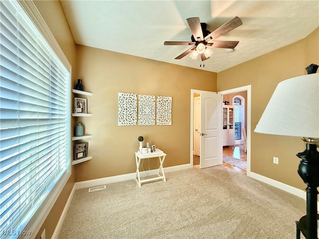 misc room with carpet floors, ceiling fan, and a healthy amount of sunlight