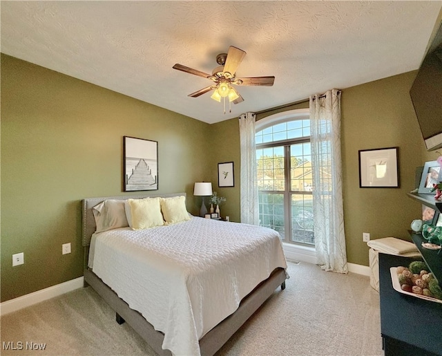 bedroom featuring light carpet, a textured ceiling, and ceiling fan