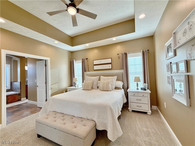 carpeted bedroom featuring multiple windows, ceiling fan, ensuite bathroom, and a textured ceiling