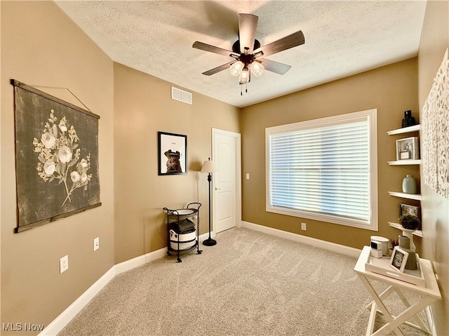 miscellaneous room featuring ceiling fan, light colored carpet, and a textured ceiling