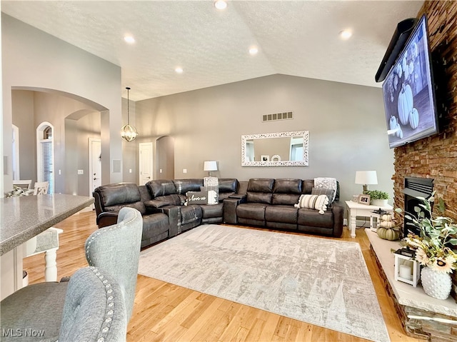 living room featuring hardwood / wood-style flooring, a fireplace, a textured ceiling, and a chandelier