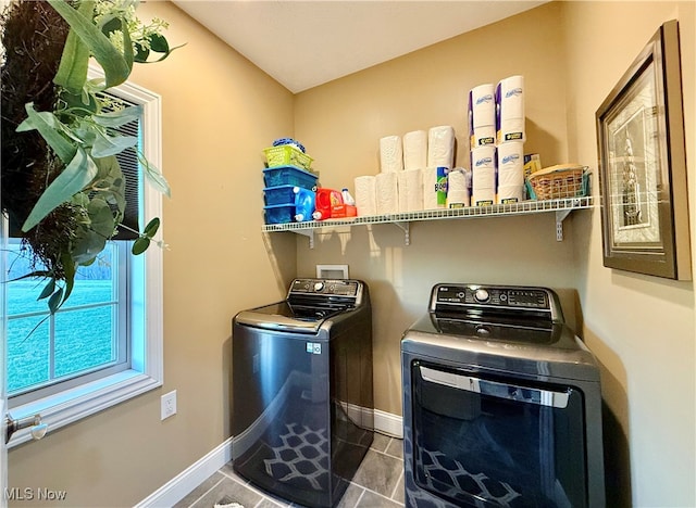 clothes washing area with dark tile patterned flooring and washing machine and clothes dryer