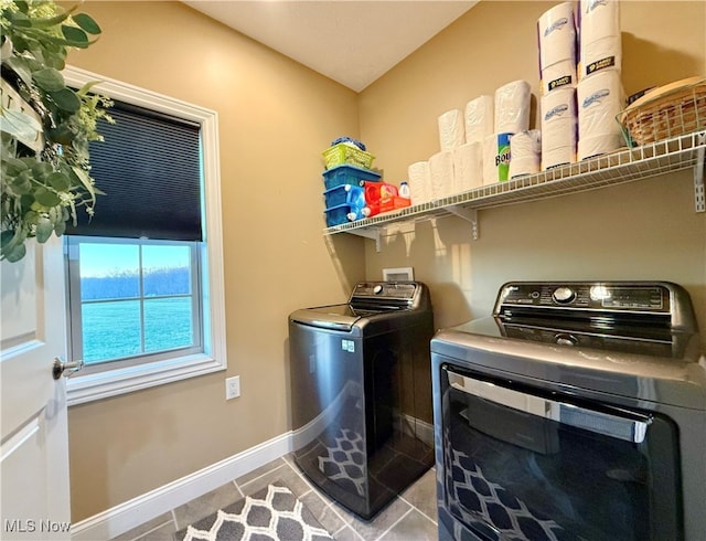 clothes washing area with light tile patterned floors and washer and clothes dryer