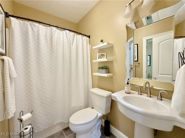 bathroom featuring sink, toilet, a textured ceiling, and tile patterned floors