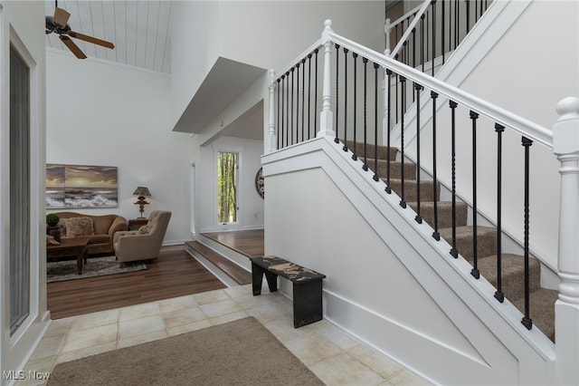 stairs featuring ceiling fan, wood-type flooring, and a high ceiling