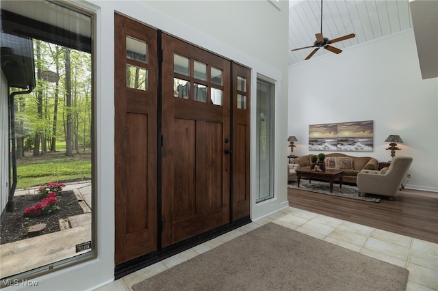 foyer with high vaulted ceiling, ceiling fan, light tile patterned flooring, and a wealth of natural light