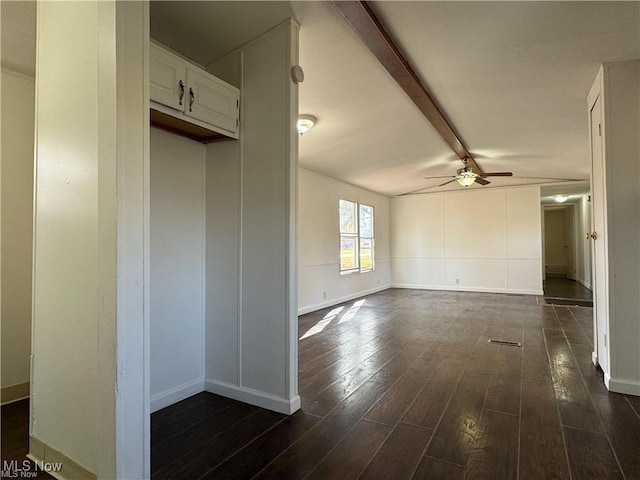 empty room featuring dark hardwood / wood-style floors, ceiling fan, and beam ceiling