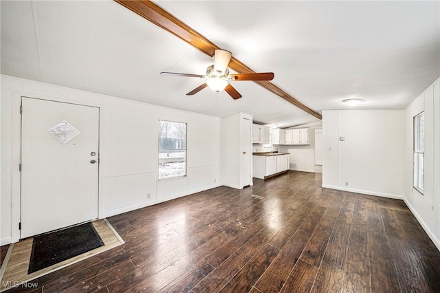 unfurnished living room featuring dark wood-type flooring, lofted ceiling with beams, and ceiling fan