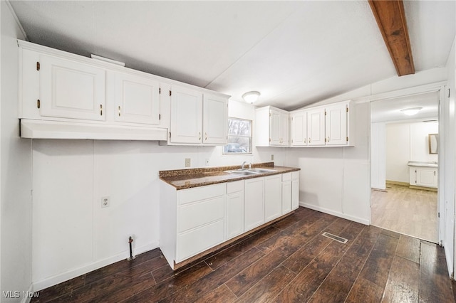 kitchen with white cabinetry, sink, dark wood-type flooring, and lofted ceiling with beams