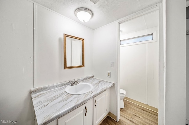 bathroom featuring vanity, toilet, hardwood / wood-style floors, and a textured ceiling