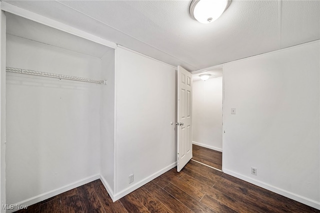 unfurnished bedroom with a closet, dark hardwood / wood-style flooring, and a textured ceiling