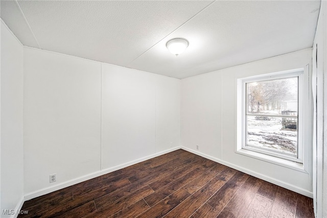 spare room with dark hardwood / wood-style flooring and a textured ceiling