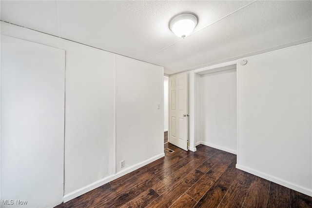 unfurnished bedroom featuring a textured ceiling and dark hardwood / wood-style flooring