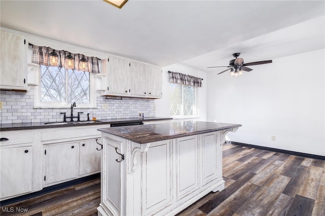 kitchen featuring sink, ceiling fan, dark hardwood / wood-style floors, a center island, and decorative backsplash