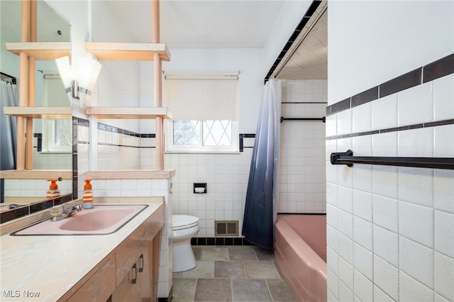 full bathroom with tile walls, vanity, toilet, and shower / tub combo