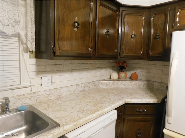 kitchen with dark brown cabinetry, white appliances, sink, and tasteful backsplash