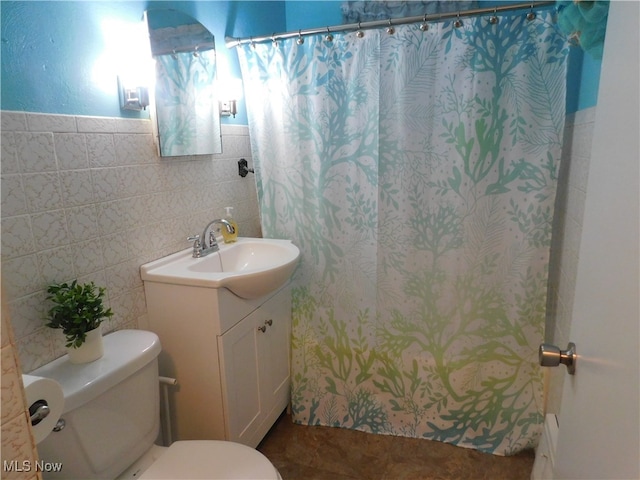 bathroom with vanity, toilet, and tile walls