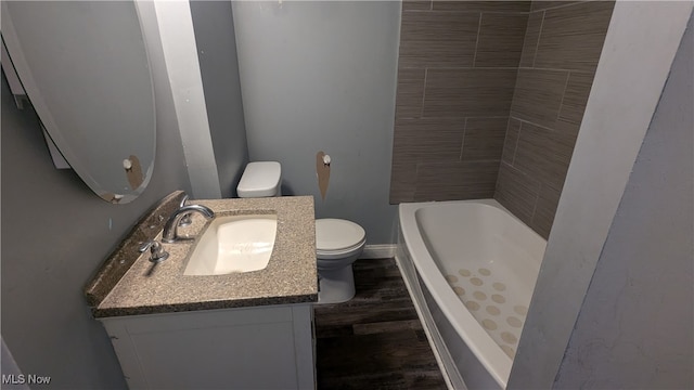 bathroom featuring wood-type flooring, a tub to relax in, toilet, and vanity