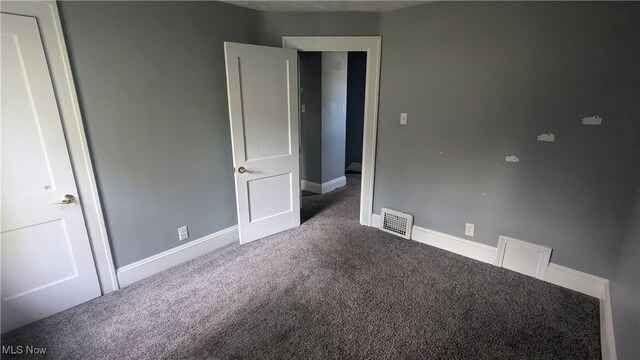 unfurnished bedroom with dark colored carpet