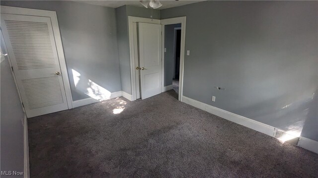 unfurnished bedroom with a closet and dark colored carpet