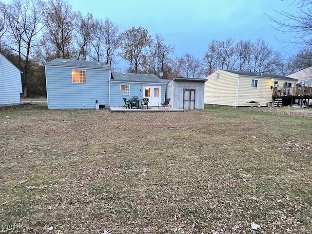 back of property featuring a storage shed, a patio area, a yard, and a deck