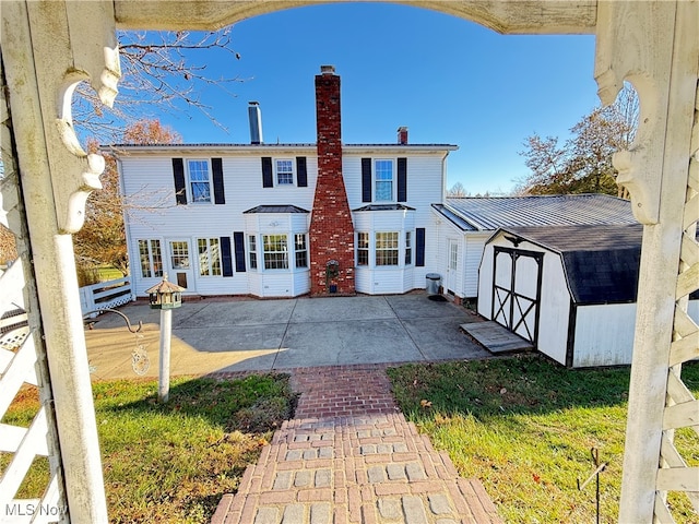 back of house with a patio area and a storage unit