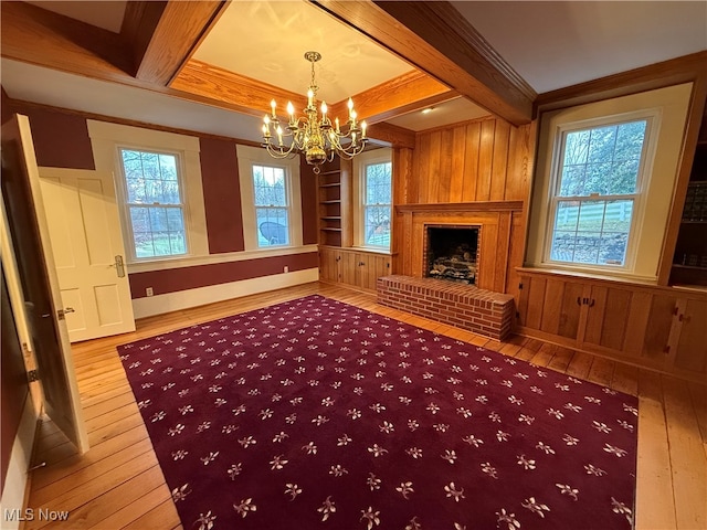 unfurnished living room featuring a fireplace, beamed ceiling, hardwood / wood-style floors, and plenty of natural light