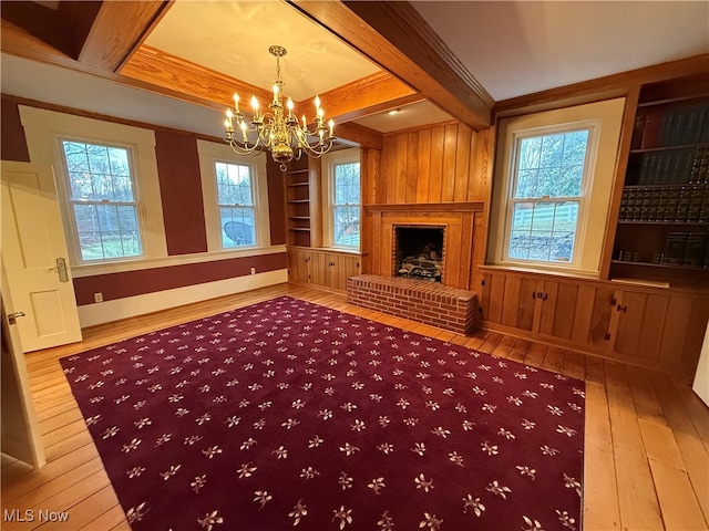 unfurnished living room with a brick fireplace, hardwood / wood-style flooring, plenty of natural light, and built in shelves