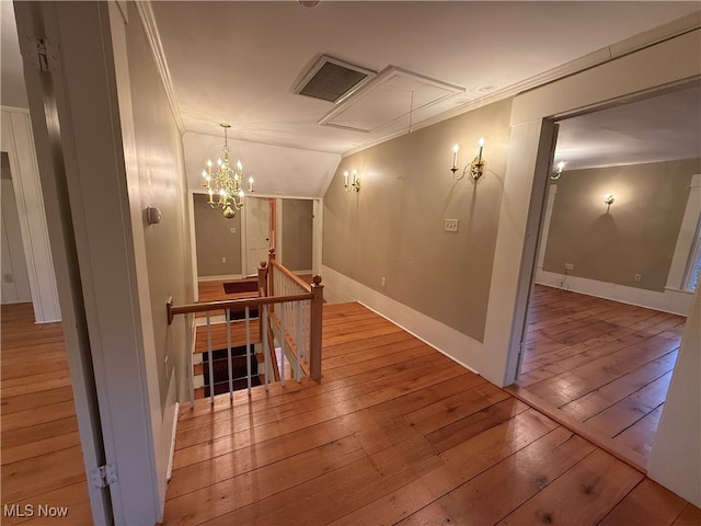 corridor with lofted ceiling, hardwood / wood-style floors, and ornamental molding