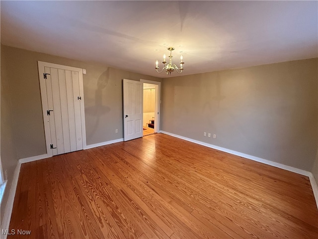 spare room with an inviting chandelier and light wood-type flooring