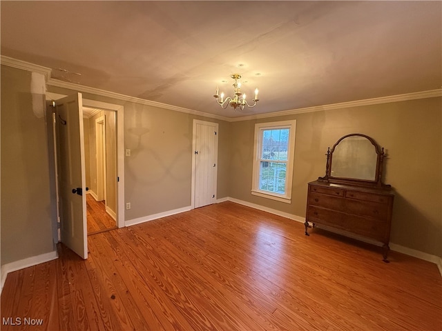 unfurnished bedroom featuring hardwood / wood-style flooring, ornamental molding, and a notable chandelier