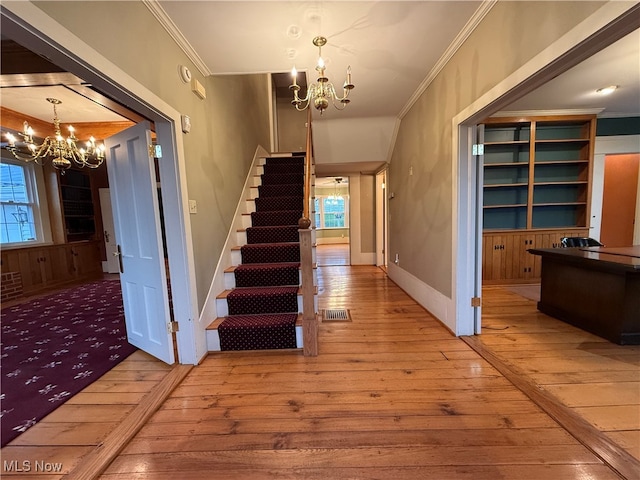 stairs featuring ornamental molding, wood-type flooring, and a healthy amount of sunlight