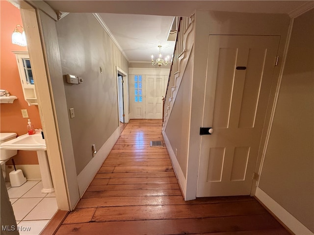 corridor featuring ornamental molding, light hardwood / wood-style floors, and a notable chandelier