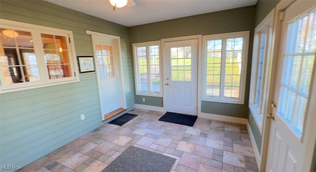 doorway to outside with wood walls and ceiling fan