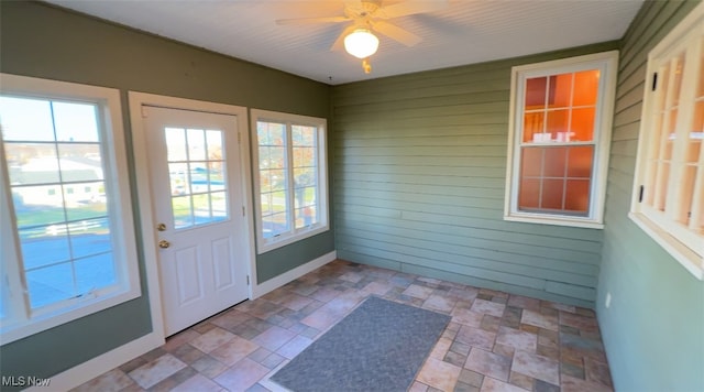 doorway with wood walls and ceiling fan