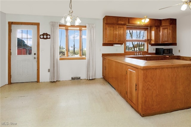 kitchen featuring a healthy amount of sunlight, hanging light fixtures, and ceiling fan with notable chandelier