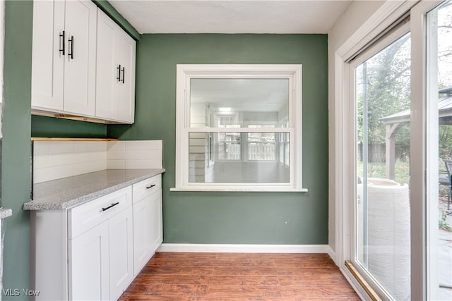 kitchen with white cabinetry, light stone counters, and hardwood / wood-style flooring