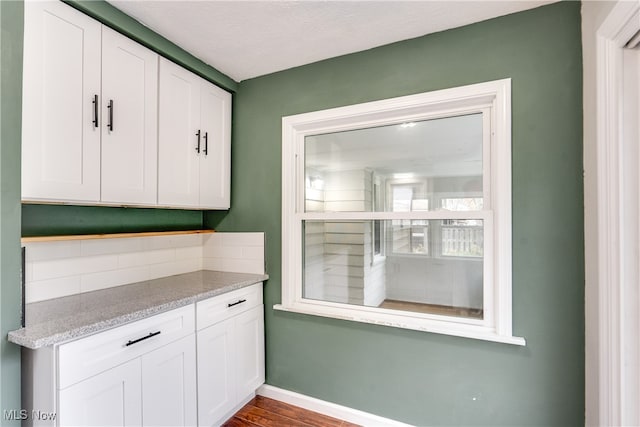 kitchen featuring hardwood / wood-style floors, white cabinets, decorative backsplash, and a textured ceiling