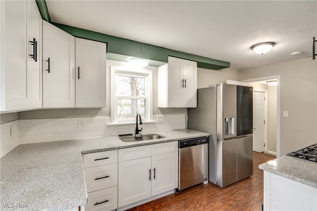 kitchen with light stone countertops, white cabinetry, sink, stainless steel appliances, and dark hardwood / wood-style flooring