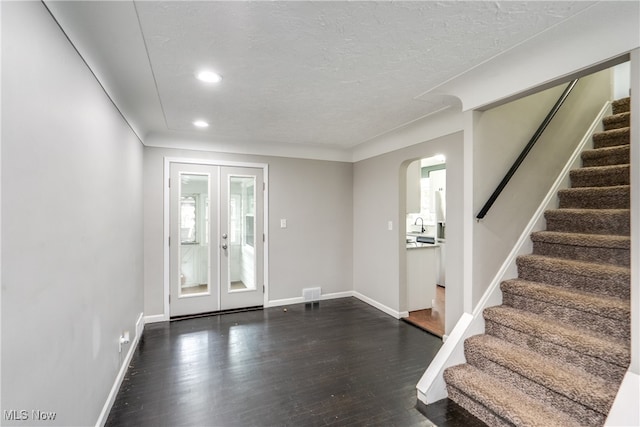 foyer entrance featuring a textured ceiling, dark hardwood / wood-style floors, and french doors